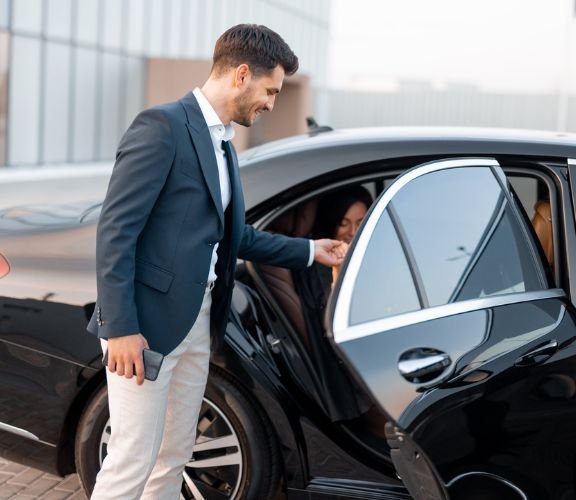 A man holding hand of a women, coming out of black car.