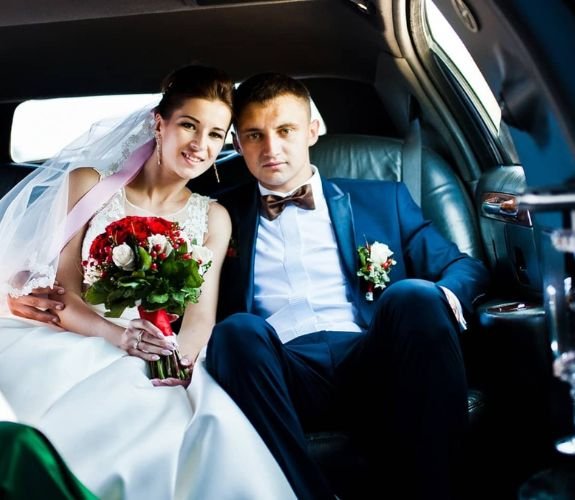 Bride and groom sitting in limousine