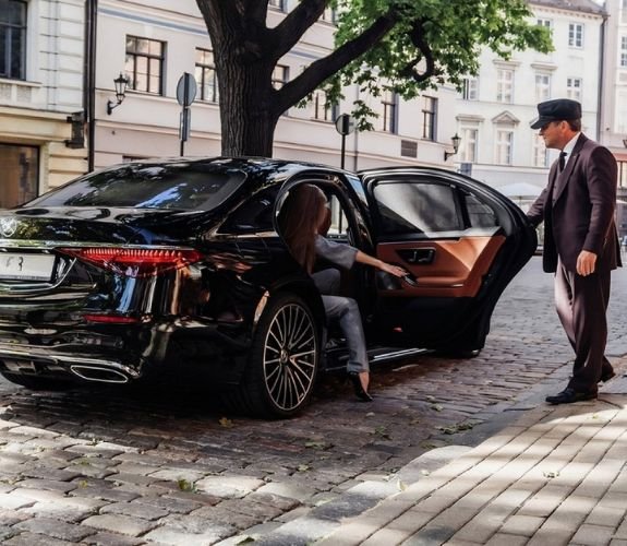 Chauffeur helping a lady coming out of a luxury car