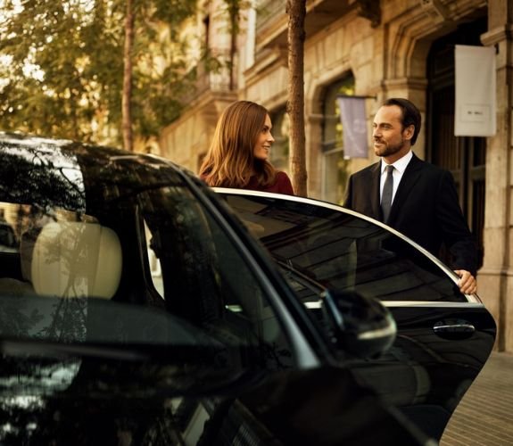 Chauffeur opening car door for woman