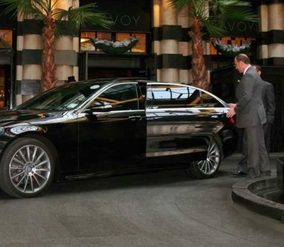 Chauffeur opening luxury car at hotel