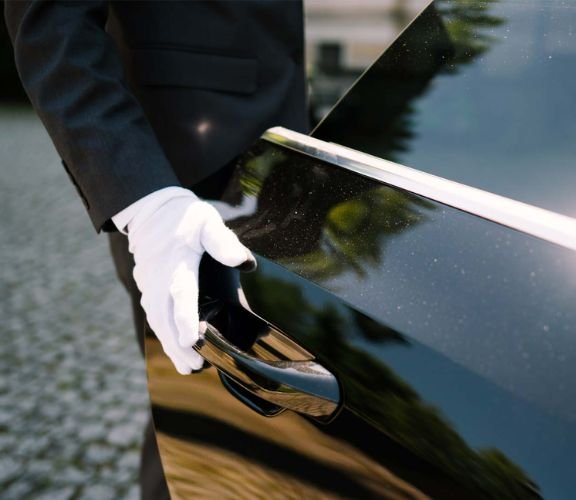 Chauffeur opening the door of a black car