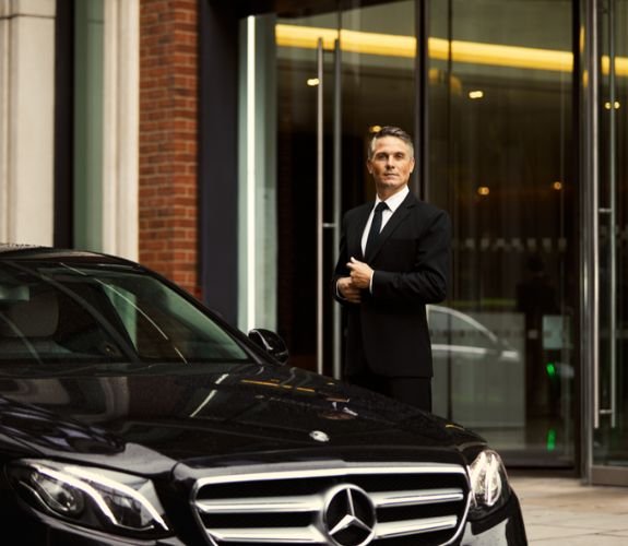 Chauffeur standing beside Mercedes car