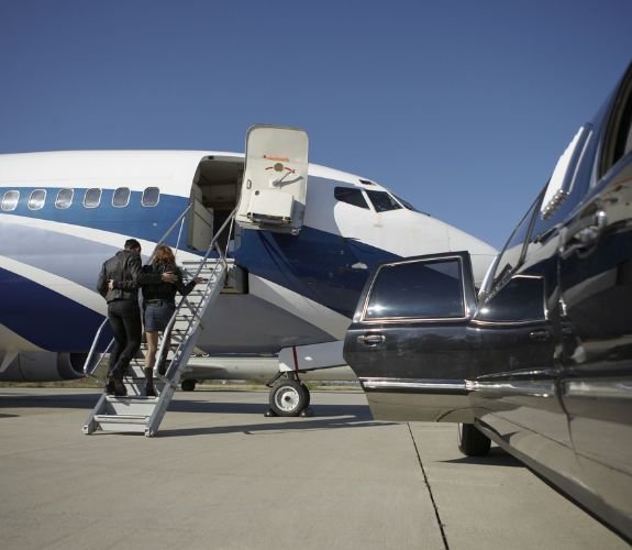 Couple boarding plane beside limousine