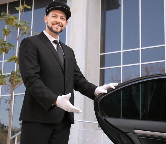 Smiling chauffeur holding car door open