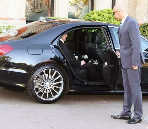 chauffeur assisting a businessman coming out of a car